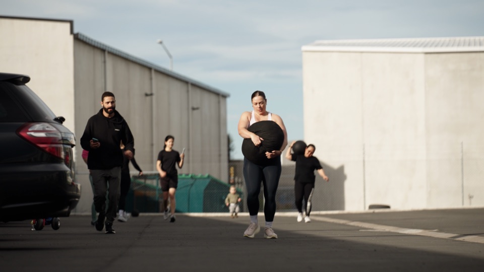 Players carry sandbags and medicine balls down the lane